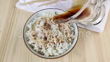 煮白的长粒大米用酱油浇水.. 烹饪饮食简餐，亚洲美食.. 圆碗，木桌，